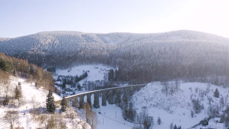 Winterlandschaft-Mit-Einem-Steinernen-Eisenbahnviadukt-Im-Fallenden-Schnee,-Sonnig