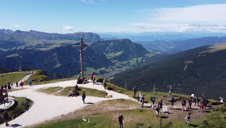 Seceda-at-South-Tyrol,-Italian-Alps,-Dolomites,-Italy---Aerial-Drone-View-of-Jesus-Statue,-Tourists-and-Mountain-Valley