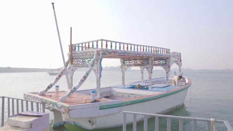 Worker-Cleaning-Sightseeing-Boat-At-Keenjhar-Lake-In-Thatta,-Pakistan