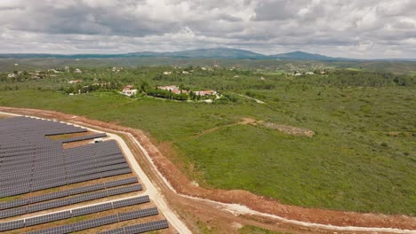 Long-aerial-shot-of-a-solar-farm-and-beautiful-villas-in-the-Portuguese-countryside,-concept-for-the-contrast-between-nature-and-technology,-tradition-and-modernity