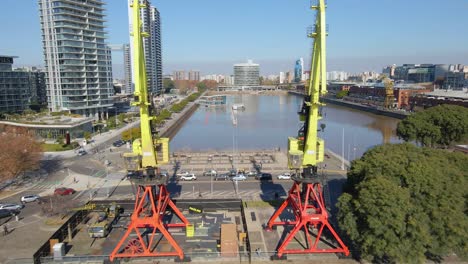 Aerial-view-of-a-waterway-flying-between-two-cranes-over-a-bridge-at-Buenos-Aires-city