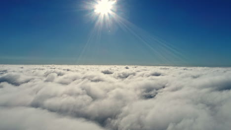 Epic-drone-shot-over-white-clouds-with-sunbeam-and-blue-sky-in-background---High-angle-backwards-flight-in-space