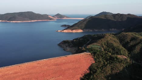 Aerial-backward-movement-shot-over-the-dam-connecting-two-islands-in-the-Hong-Kong-Geographical-Park-in-Sai-Kung-on-a-beautiful-sunny-day