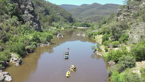 Aerial:-Rafting-group-paddles-out-of-rocky-river-canyon-on-flat-water