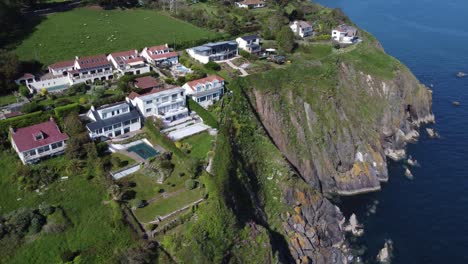 A-stunning-drone-shot-slowly-curving-to-the-right-as-it-overflies-beautiful-houses-perched-at-the-top-of-some-south-devon-cliffs