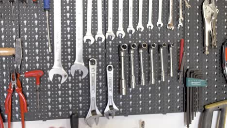 Tools-arranged-on-a-wall-workshop-including-wrenches,-spanners,-pliers,-cutters-and-hammer,-Dolly-left-right-shot