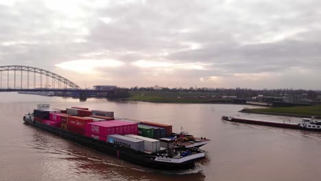 Aerial-Circle-Dolly-Of-Excelsior-Cargo-Ship-And-Barge-Transporting-Cargo-Containers-On-River-Noord-With-Crezeepolder-In-Background