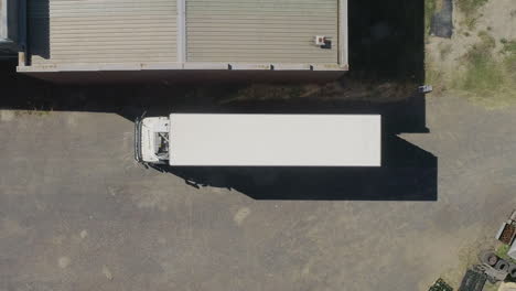 Smooth-aerial-ascent-above-truck-about-to-leave-depot