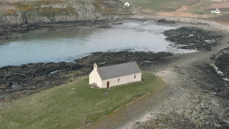 An-aerial-view-of-Eglwys-Cwyfan-church-on-an-overcast-day,-flying-right-to-left-around-the-church,-Anglesey,-North-Wales,-UK