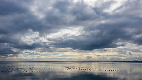aerial-Time-lapse-of-the-clouds-moving-above-a-still-ocean,-reflection-of-clouds-in-the-water
