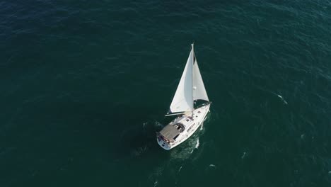 Luxurious-white-sailing-yacht-with-billowing-sails-is-blown-forward-as-she-swings-on-the-small-waves-in-the-clear-blue-Mediterranean-off-the-coast-of-Herzeliya-in-Israel