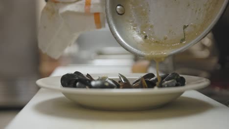 Chef-Drizzling-Sauce-onto-Mussels-in-a-Kitchen