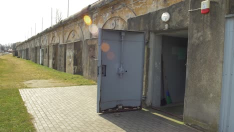 Entrance-with-the-steel-door-into-the-concrete-bomb-shelter-to-hide-civil-people,-an-underground-apocalypse-bunker-built-in-old-coastal-fortification,-sunny-day,-lens-flare,-wide-shot