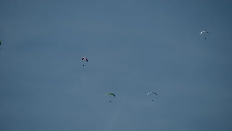Wide-shot-showing-group-of-paraglider-flying-against-blue-sky-and-sunlight-in-the-air