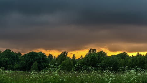 Landscape-time-lapse-of-storm-clouds-over-a-countryside-field-at-sunset
