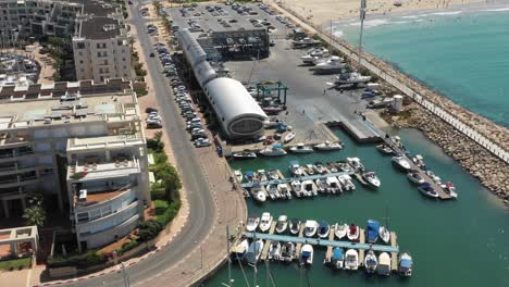 Several-ships-are-moored-at-a-jetty-while-other-ships-are-parked-in-the-shed-on-the-side-on-a-summer-day-in-Herzeliya,-Israel