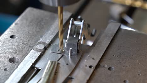 Titanium-coated-drill-making-precise-hole-in-steel-plate-for-the-creation-of-kitchen-cutting-utensils,-Close-up-shot