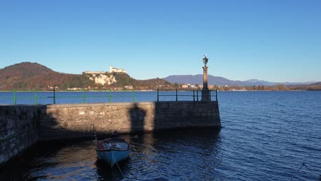 Establishing-static-shot-of-fishing-boat-moored-on-Lake-Maggiore-in-Arona-facing-fortress-of-Angera