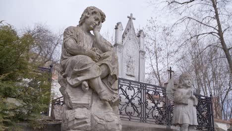 Two-Stone-Statues-in-Graveyard-in-Front-of-Big-Tombstone-in-Uzupis-Cemetery