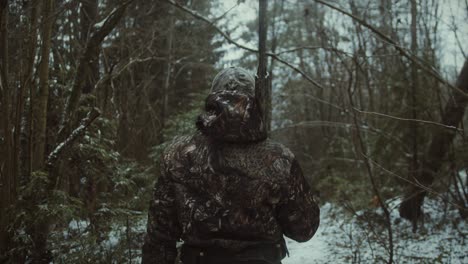 Back-view-of-a-hunter-walking-in-the-snow-with-a-rifle-and-camouflage-during-hunting-trip,-winter-hunting