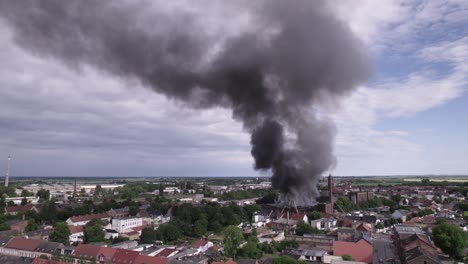 Static-aerial-shot-of-building-roof-burning-with-black-smoke-in-Kothen-Germany