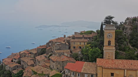 Eze-France-Aerial-v23-cinematic-low-level-drone-fly-around-hillside-town-village-with-old-medieval-buildings-and-notre-dame-de-l'assomption-church---July-2021