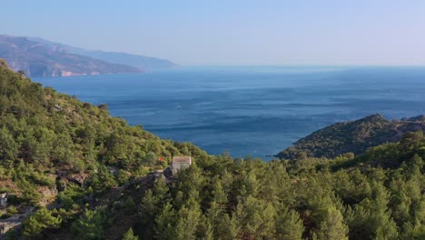wide-aerial-view-of-whats-left-of-the-abandoned-Kayakoy-village-with-one-last-building-on-top-of-a-hill-overlooking-the-blue-Mediterranean-Sea-on-a-summer-day-in-Fethiye-Turkey