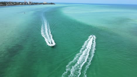 Camera-is-flying-between-boats-as-they-cross-paths-near-the-opening-of-a-small-bay-into-the-wide-ocean