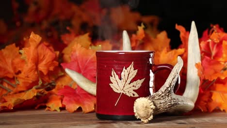 fall-themed-setting,-red-mug-or-cup-with-a-maple-leaf,-whitetail-deer-shed-antler-and-color-maple-leaves