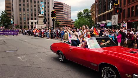 The-Grand-Marshals-ride-in-a-bright-red-convertible-car-in-Gay-Pride-Paraade-in-Portland,-Maine
