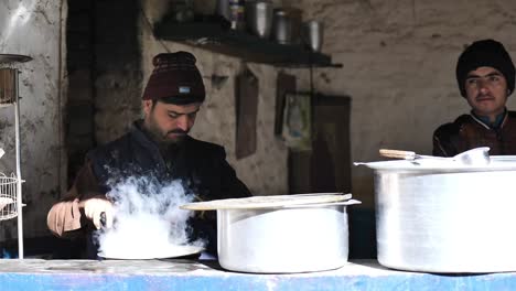 Two-men-preparing-tea-in-local-roadside-hotel-in-their-traditional-dress-standing-outdoor-in-Balochistan