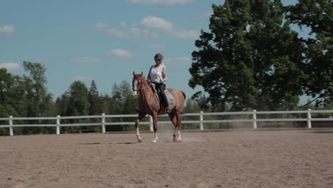 A-Caucasian-lady-and-her-beautiful-horse-trotting-elegantly-around-a-paddock-of-an-equestrian-centre-training-their-dressage-routine,-Sweden