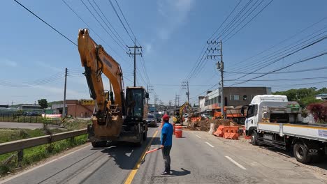 Trabajador-De-La-Construcción-Dirigiendo-El-Tráfico-En-La-Carretera-Con-Obras-Viales-En-Curso
