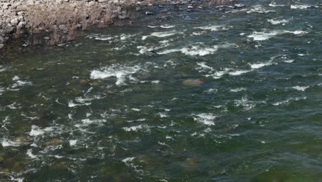 Aerial-shot-of-a-shallow-river-in-Spokane,-Washington-on-a-warm-summer-day