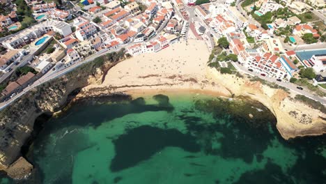 Sandy-beach-and-seaside-town-in-Algarve,-Portugal---top-down-and-reveal-by-drone