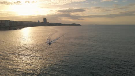 Ein-Boot-Fährt-Entlang-Der-Küste-Von-Sliema,-Malta,-Während-Die-Untergehende-Sonne-Vom-Wasser-Reflektiert-Wird