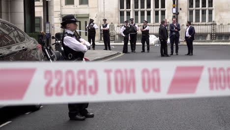 Metropolitan-police-officers-stand-behind-red-and-white-crime-scene-cordon-tape-during-a-public-order-event