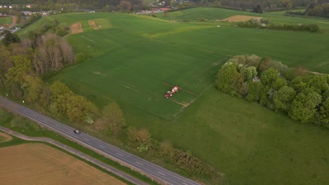 Luftaufnahmen-Einer-Großen-Wiese-In-Hessen,-Wo-Ein-Bauer-Seinen-Traktor-Mit-Wasser-Und-Einer-Sprinkleranlage-Fährt