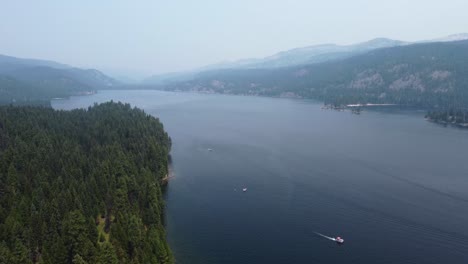 Drone-shot-of-forest-on-the-shore-of-Lake-Payette-with-mountains-in-the-background