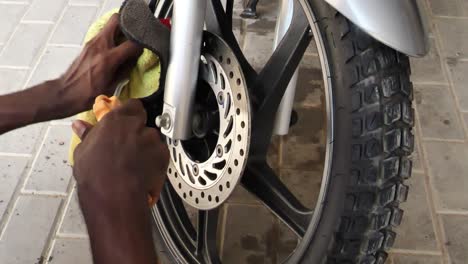 Mechanic-Using-Microfibre-Cloth-To-Dry-Disc-Brake-With-Compressed-Air-Pump-On-Front-Tyre-Of-Honda-CBF150F