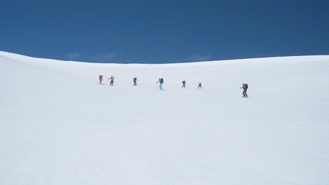 Team-of-hikers-climbing-up-steep-snowy-slope-in-Svalbard,-view-from-bellow