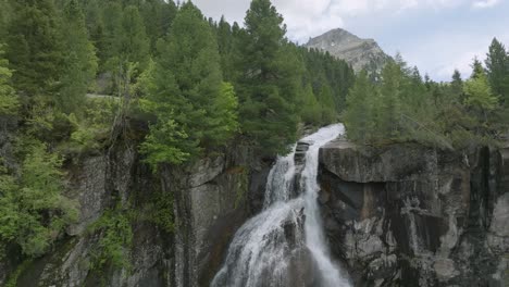 Drone-shot-showing-falling-water-down-the-rocky-waterfall-in-Dolomites-Mountains---tilt-down