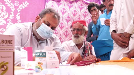 Anciano-Hablando-Con-Un-Médico-Auxiliar-Junto-A-Una-Carpa-Durante-El-Alivio-De-Las-Inundaciones-En-Pakistán