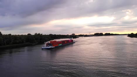 Luftaufnahme-Der-Backbordseite-Des-Frachtcontainertransportschiffs-Levante,-Das-Gegen-Den-Sonnenuntergangshimmel-Durch-Die-Oude-Maas-Navigiert