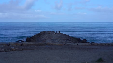 Distant-view-of-three-men-fishing-on-breakwater,-Furadouro-Beach,-Portugal