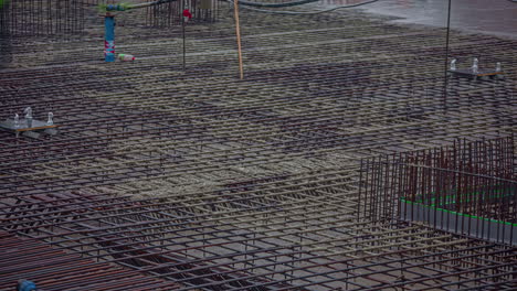 Overview-shot-of-big-construction-site-with-workers-pouring-cement-over-steel-rods-in-timelapse-at-daytime