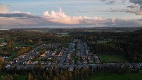 Wide-establishing-shot-of-an-American-developed-neighborhood-surrounded-by-forests-and-cloudy-skies-at-sunset