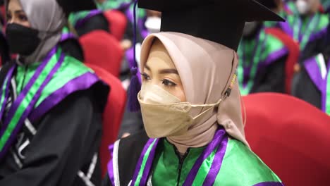 Happy-Asian-young-beautiful-graduate-female-student-with-University-degree-sit-after-graduation-wearing-black-cap-with-purple-tassels