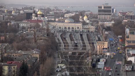 Eine-Luftaufnahme-Mit-Blick-Auf-Die-Stadt-Odessa,-Während-Ein-Zug-Den-Bahnhof-Verlässt,-Mit-Reich-Verzierten-Kirchen-Und-Dem-Schwarzen-Meer-Im-Hintergrund
