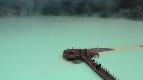 tourists-on-platform-bridge-of-extreme-and-dangerous-sulfur-lake-Kawah-Putih-in-Bandung-Indonesia,-aerial
